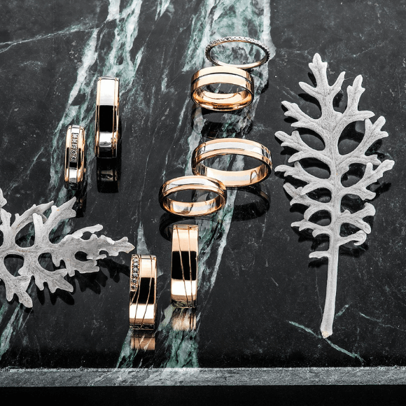Keli auksiniai žiedai su skirtingais dizainais ant marmurinio paviršiaus