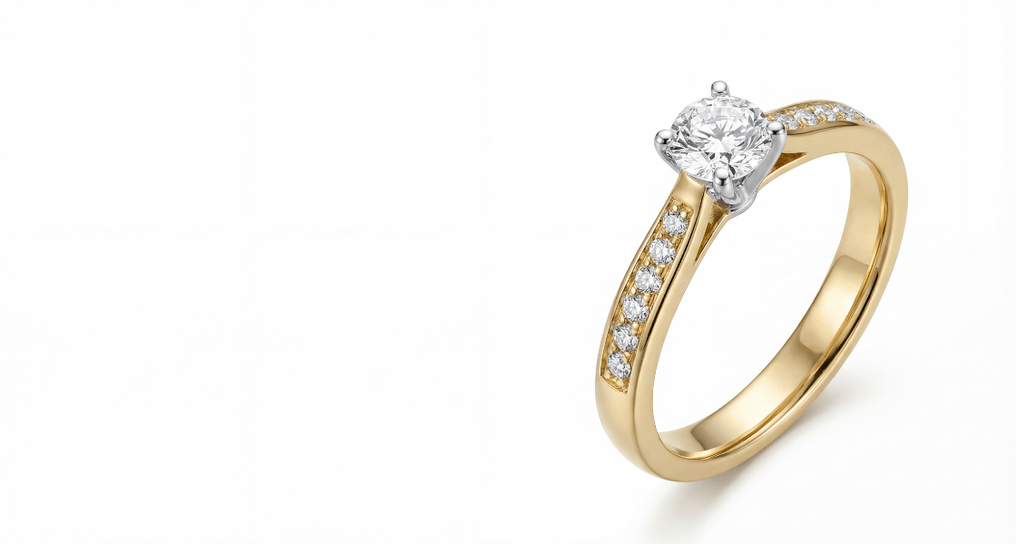 Sužadėtuvių žiedas iš geltono aukso su centriniu apvaliu briliantu ir šonuose inkrustuotais mažais deimantais ant balto fono