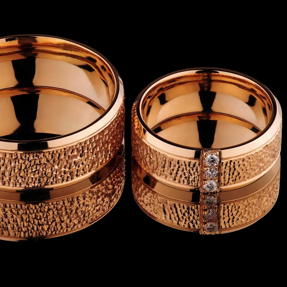 Vestuviniai žiedai Nr. V168 – 585 prabos raudono aukso vestuviniai žiedai su tekstūriniu (grublėtu) paviršiumi ir poliruota juosta, moteriškas žiedas puoštas briliantais, bendras svoris 15 g